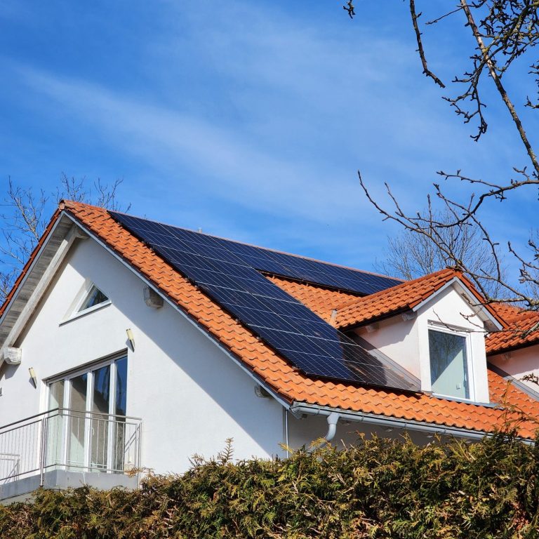 Bungalow mit Solarzellen auf dem Dach und blauem Himmel im Hintergrund.