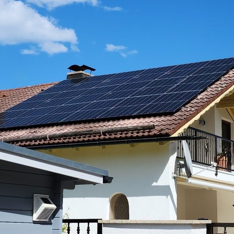 Dach mit Solarpanelen unter blauem Himmel und wenigen Wolken.